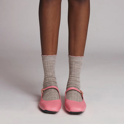 Pink shoes worn with gray socks on a neutral background