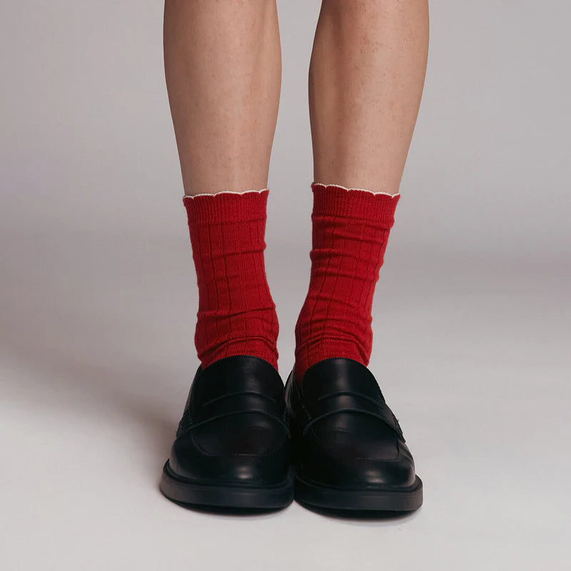 Red socks worn with black shoes on a plain background