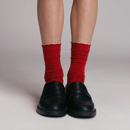 Red socks worn with black shoes on a plain background