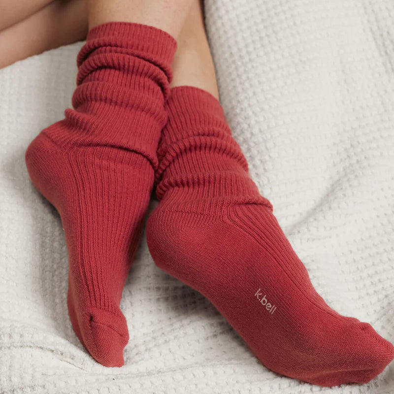 person's feet wearing wine colored socks on a white textured surface