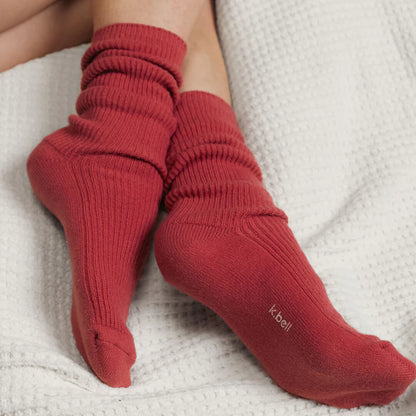 person's feet wearing wine colored socks on a white textured surface