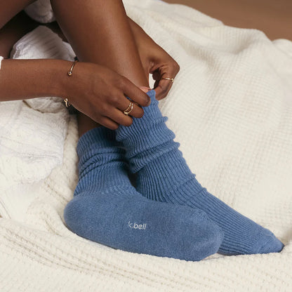 person sitting on a bed wearing demin blue slouch socks 
