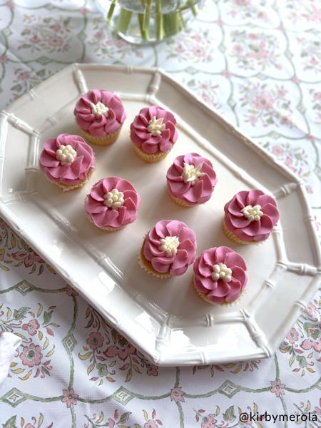 White bamboo platter set on a table with cupcakes iced with pink icing.