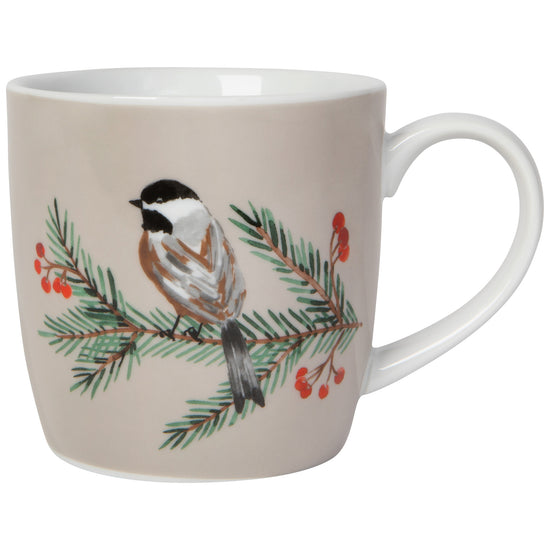 A white porcelain mug with a brown and black bird perched on a branch with green leaves and red berries