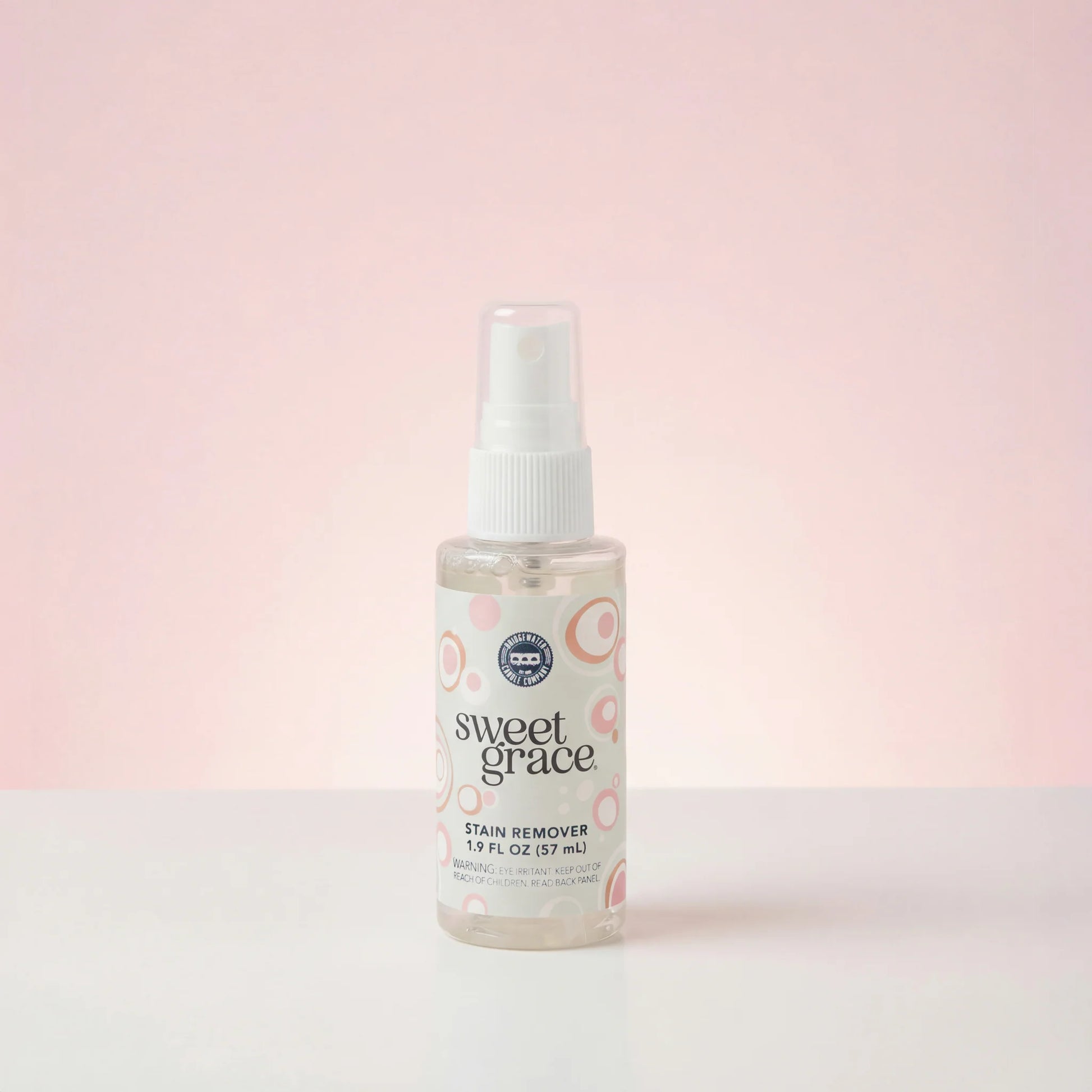 small spray bottle of sweet grace stain remover shown on a pink background
