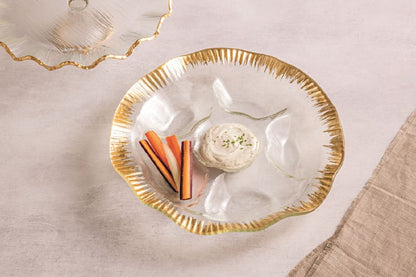 Glass dish with gold rim containing a dip and carrots on a beige surface