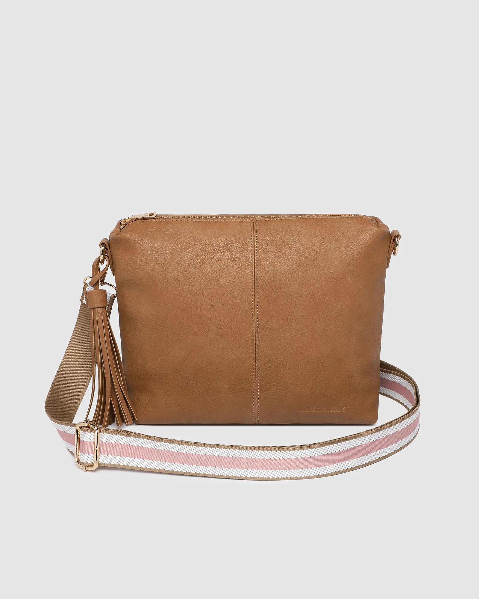 camel Daisy crossbody bag with pink striped strap draped in front of it.