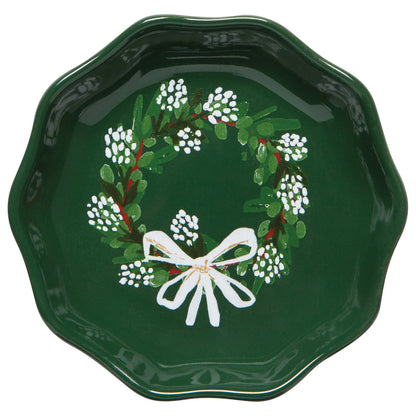 Green dish with wreath printed in the bottom, wreath has white berries in a white bow on it.