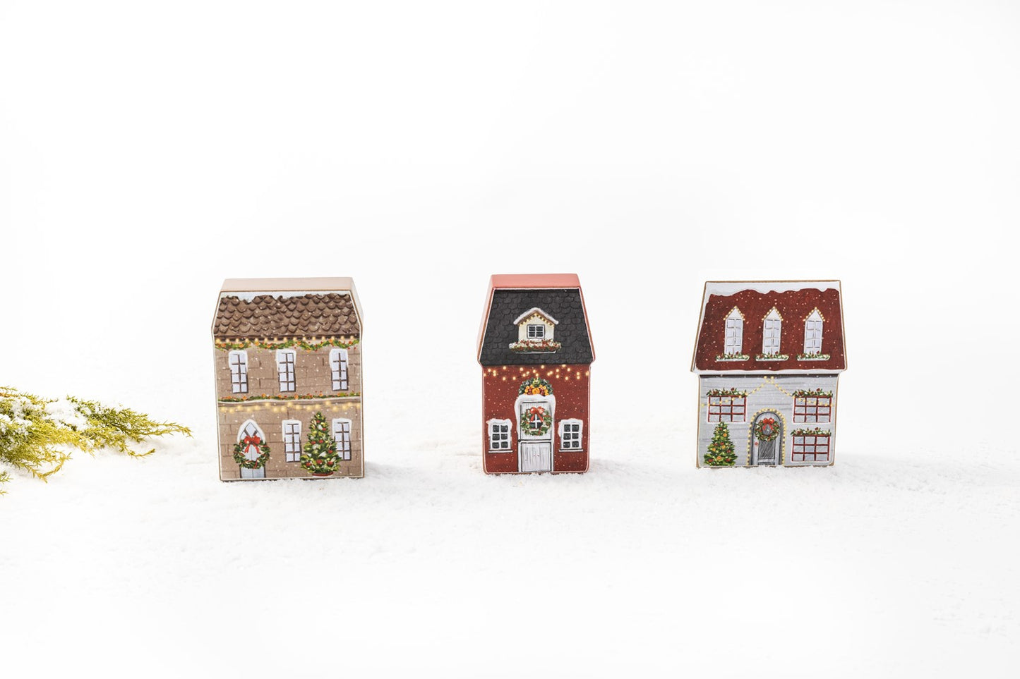 all three styles of wassail village block houses displayed against a white background next to a sprig of greenery