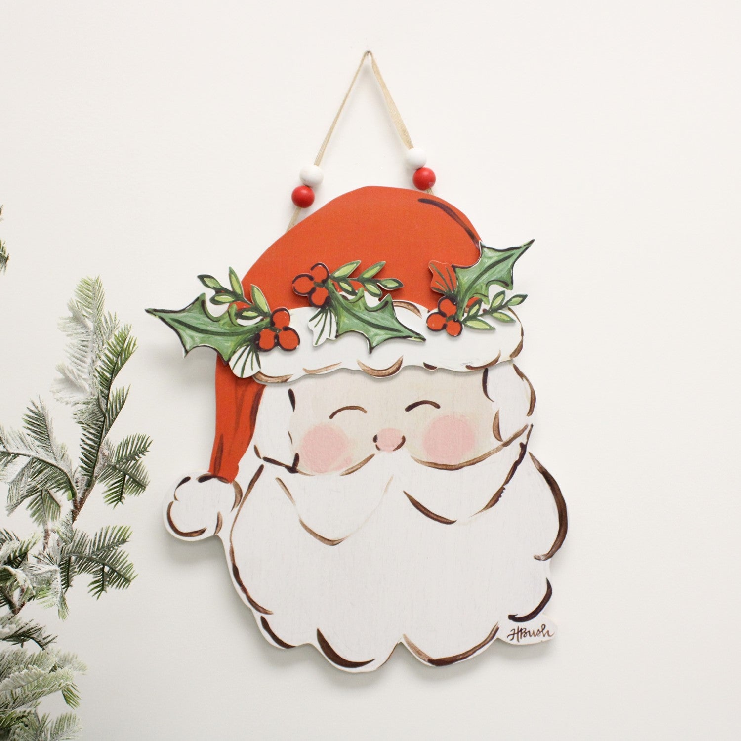 cutout santa door decor hanging against a white wall next to a tree