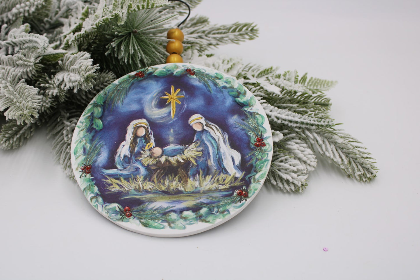 nativity scene ornaments laying on a sprig of greenery