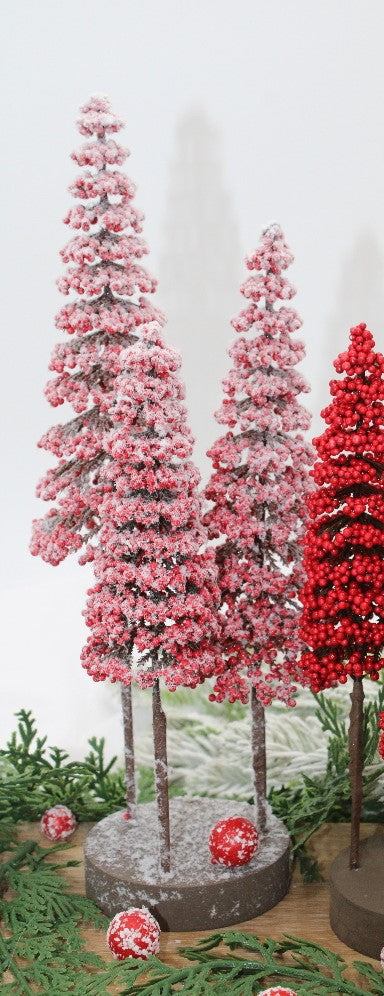 3 frosted red berry trees on a round wooden base arranged on a table with greenery