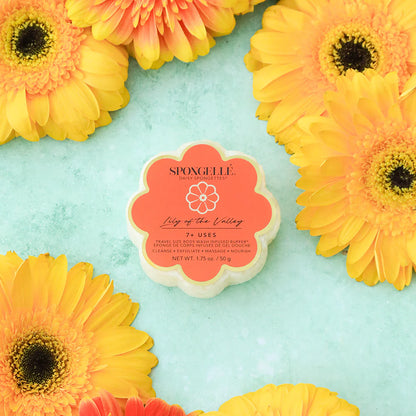 Spongelle sponge arranged with yellow and orange flowers on a light blue background