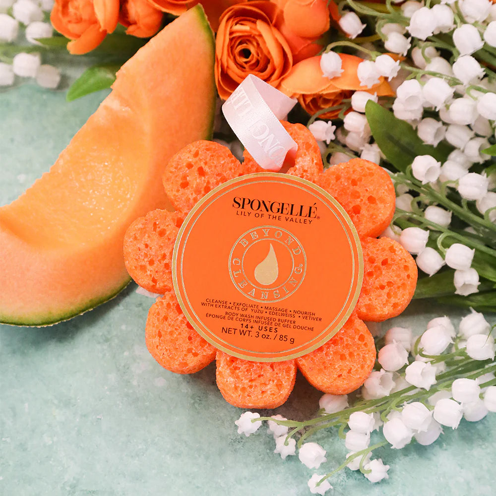 Orange flower-shaped sponge with 'Spongellé' branding on a light blue background with flowers and cantaloupe.