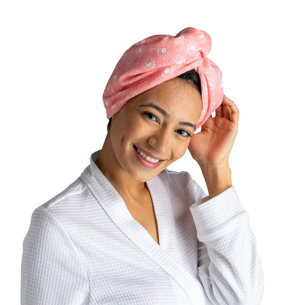 a woman modeling the pink moons Plot Twist Microfiber Turbo Towel on her hair against a white background