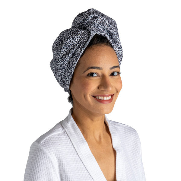 a woman modeling the black flowers Plot Twist Microfiber Turbo Towel on her hair against a white background