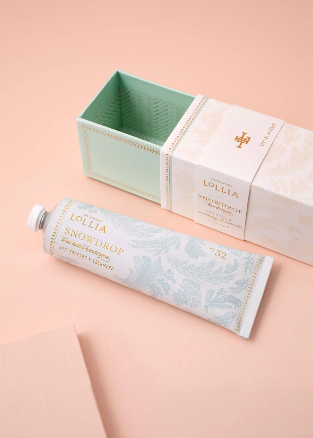 Lollia Snowdrop hand cream with packaging on a peach background