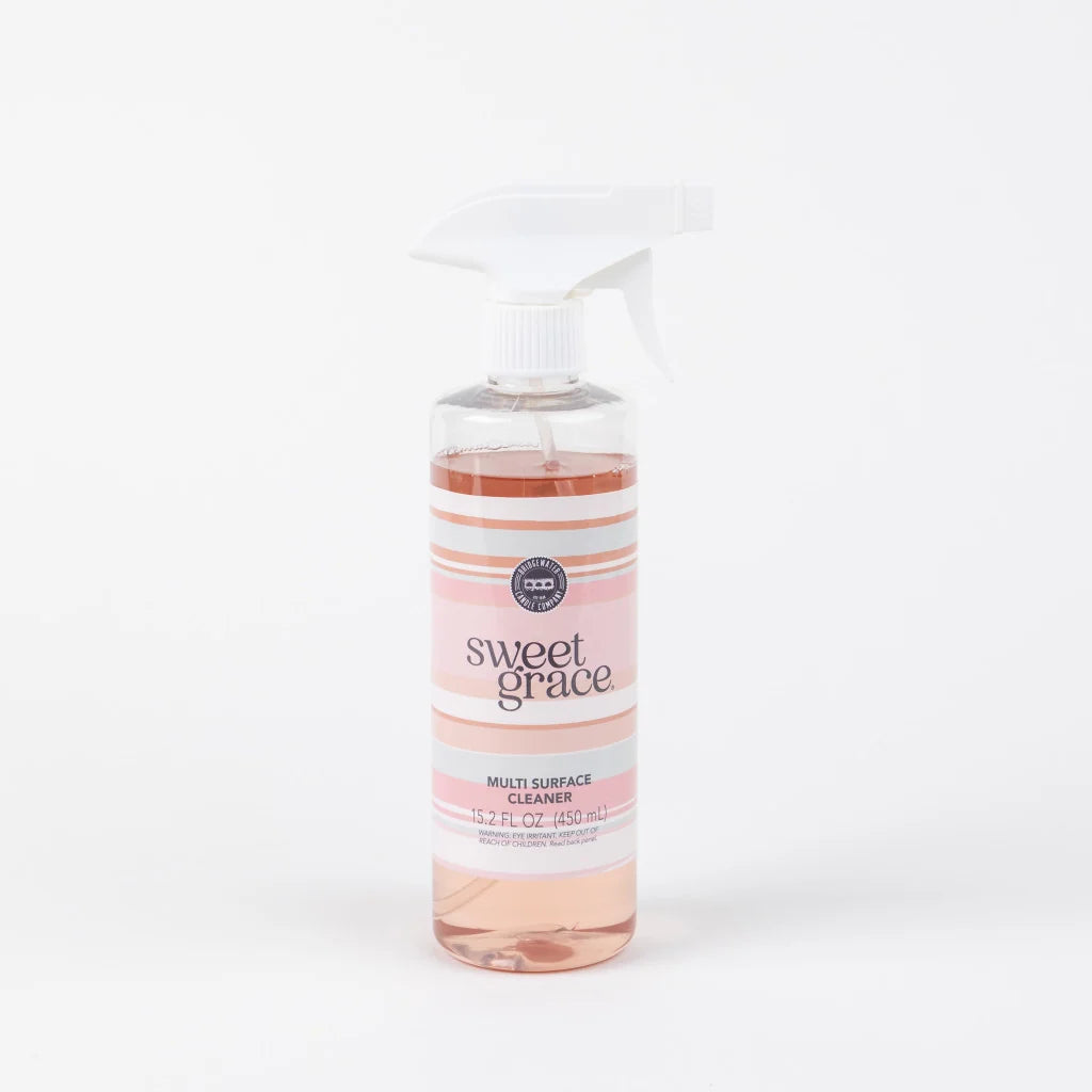 A bottle of Sweet Grace Multi-Surface Cleaner with a white spray trigger top and a pink and white striped label, shown on a clean white background.