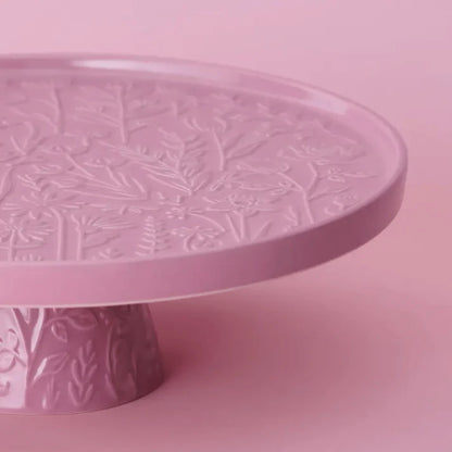 close-up of Pink cake stand embossed with floral design on a pink background