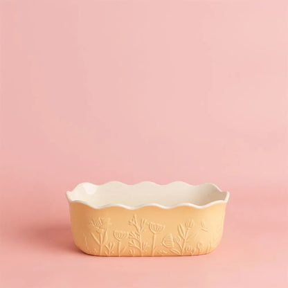 Decorative yellow loaf pan with floral embossing on a pink background