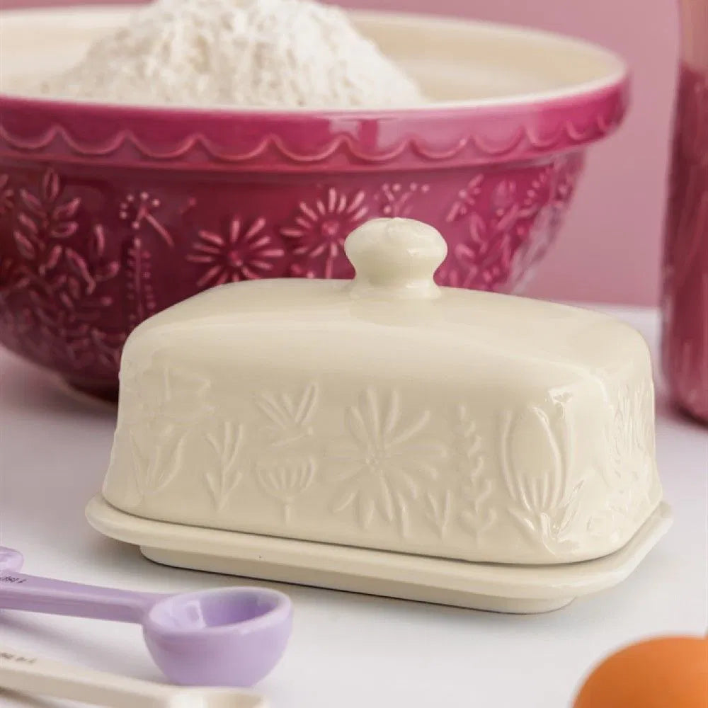 White butter dish with floral patterns on a pink background