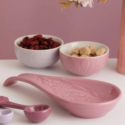 in the meadow spoon rest set on a counter with small bowls and measuring spoons
