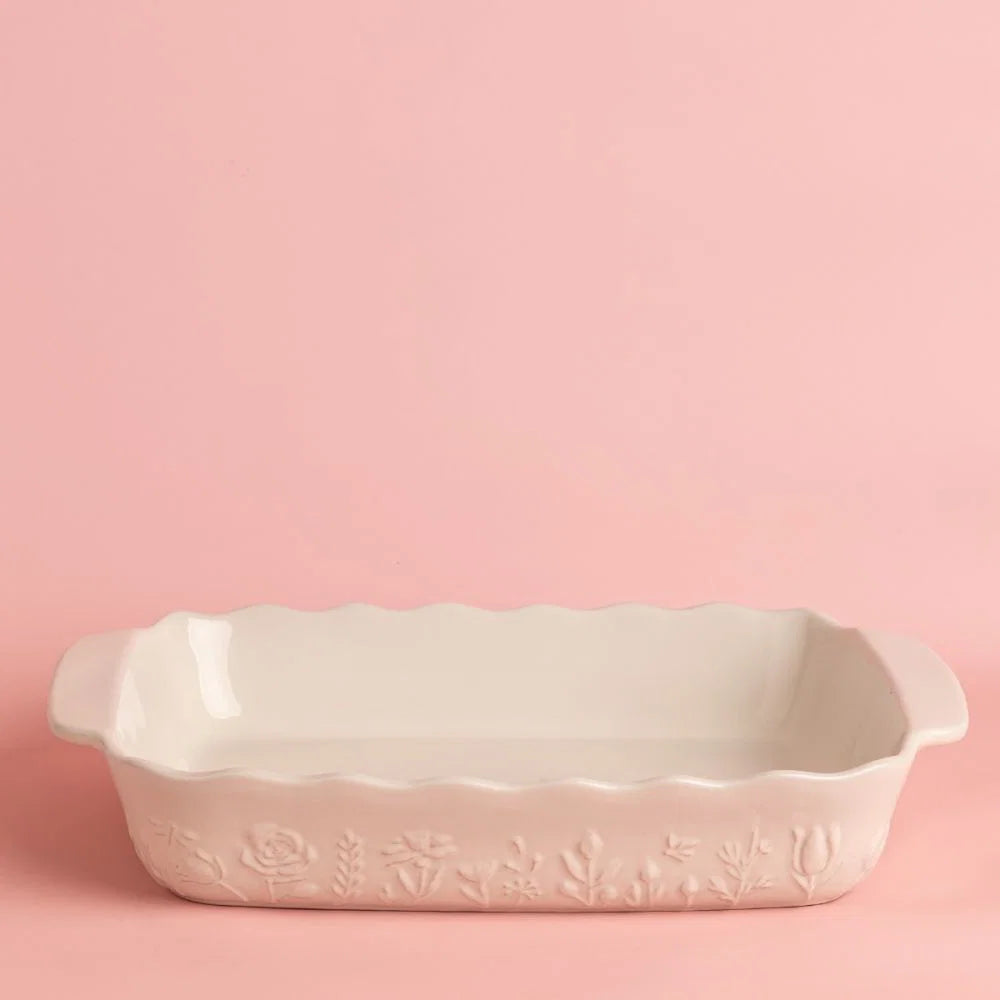 White ceramic baking dish with floral design on a pink background