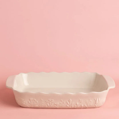 White ceramic baking dish with floral design on a pink background