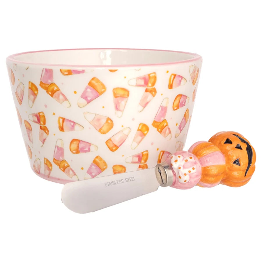 small bowl with pink candy corn design printed on it with a spreader with pumpkin handle set next to it on a white background