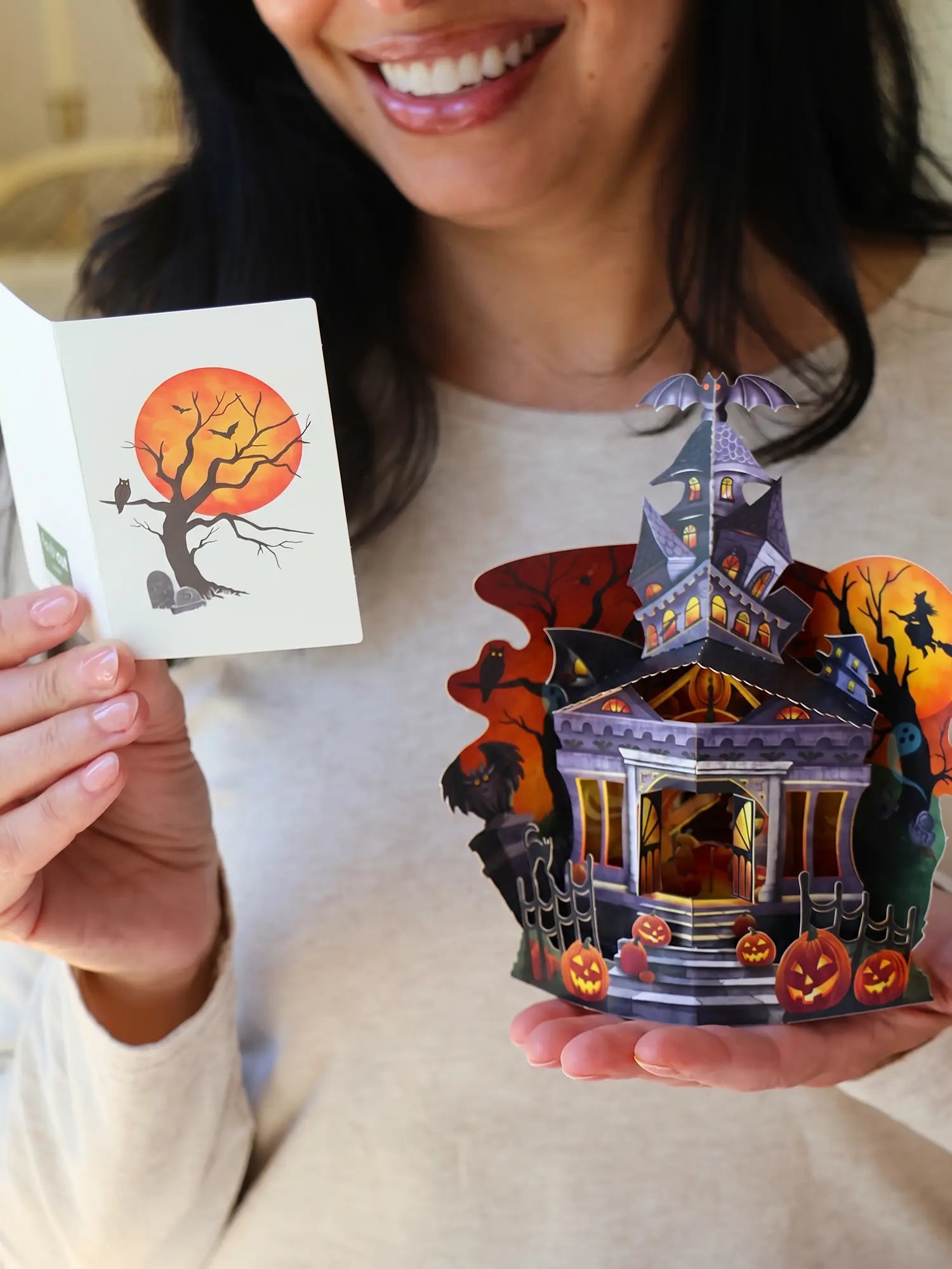 Person holding a pop-up card with a haunted house design