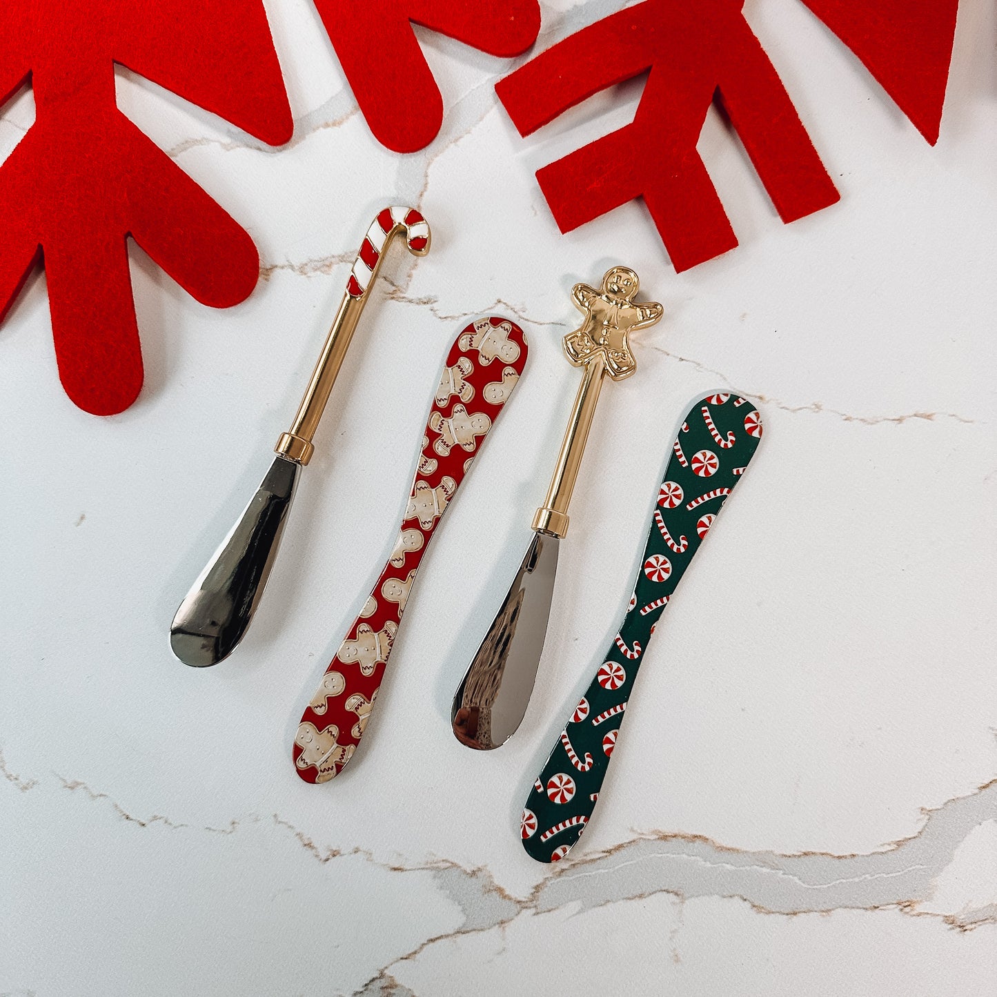 a set of four holiday spreaders with candy cane and gingerbread handles and two with gingerbread and candy canes all over.