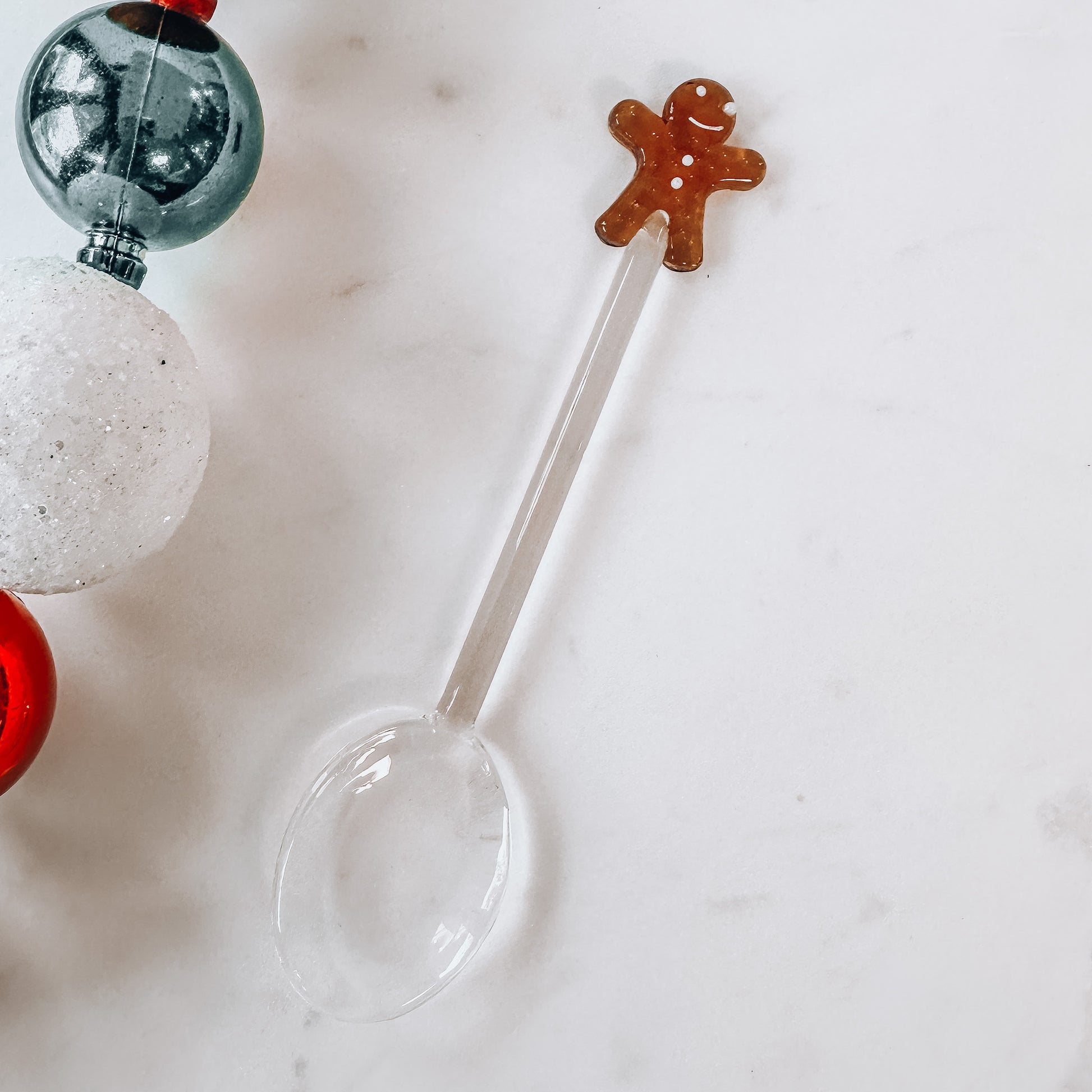 Glass Christmas spoon with gingerbread top on a marble background.