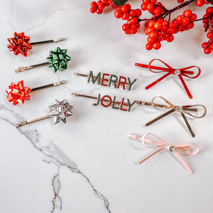 Three sets of Mud Pie Holiday Hair Clips, gift bows, Merry & Jolly Word Clips, and a set of ribbon bows with jewels.