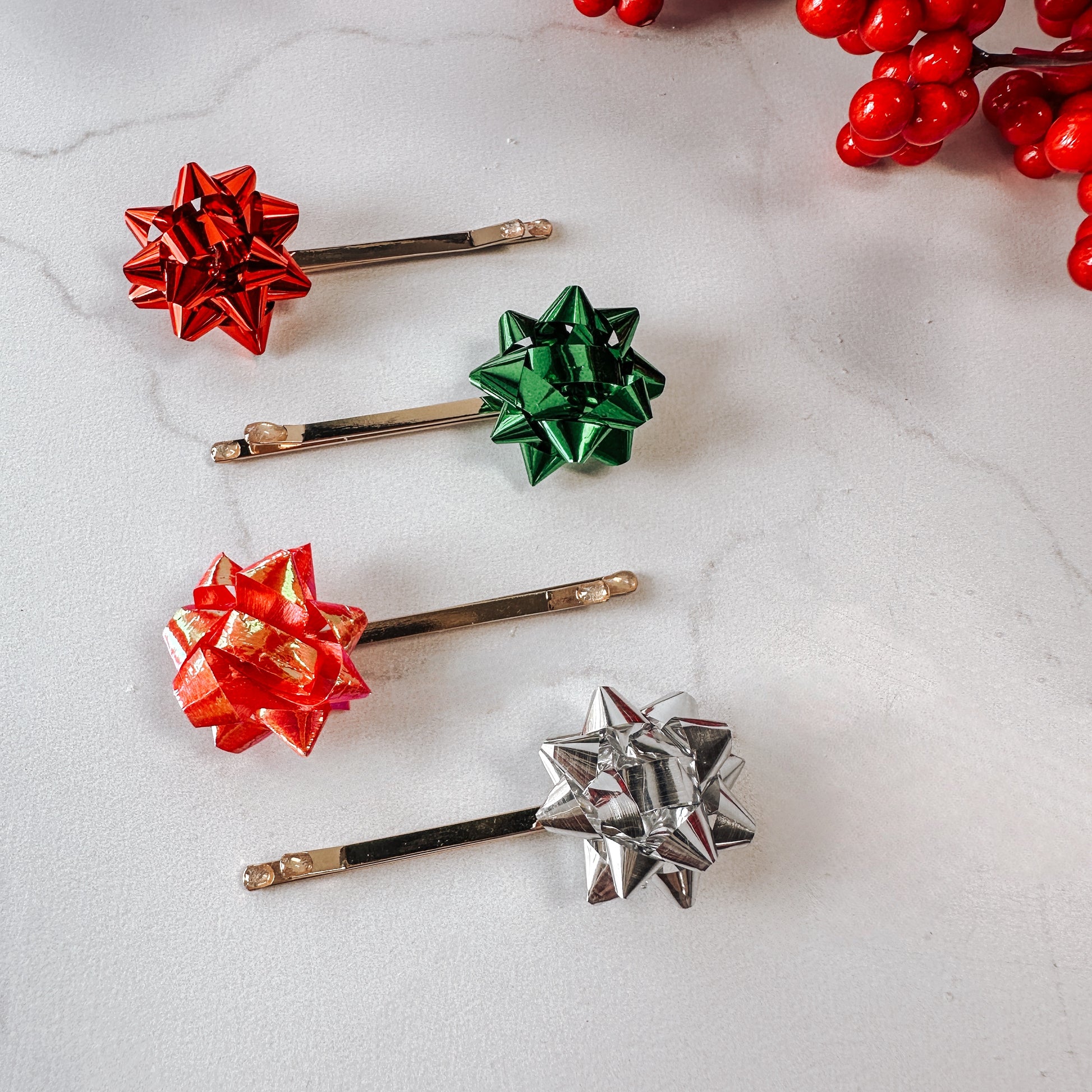 Set of four gift bows in red, green , pink, and silver on gold hairpins.