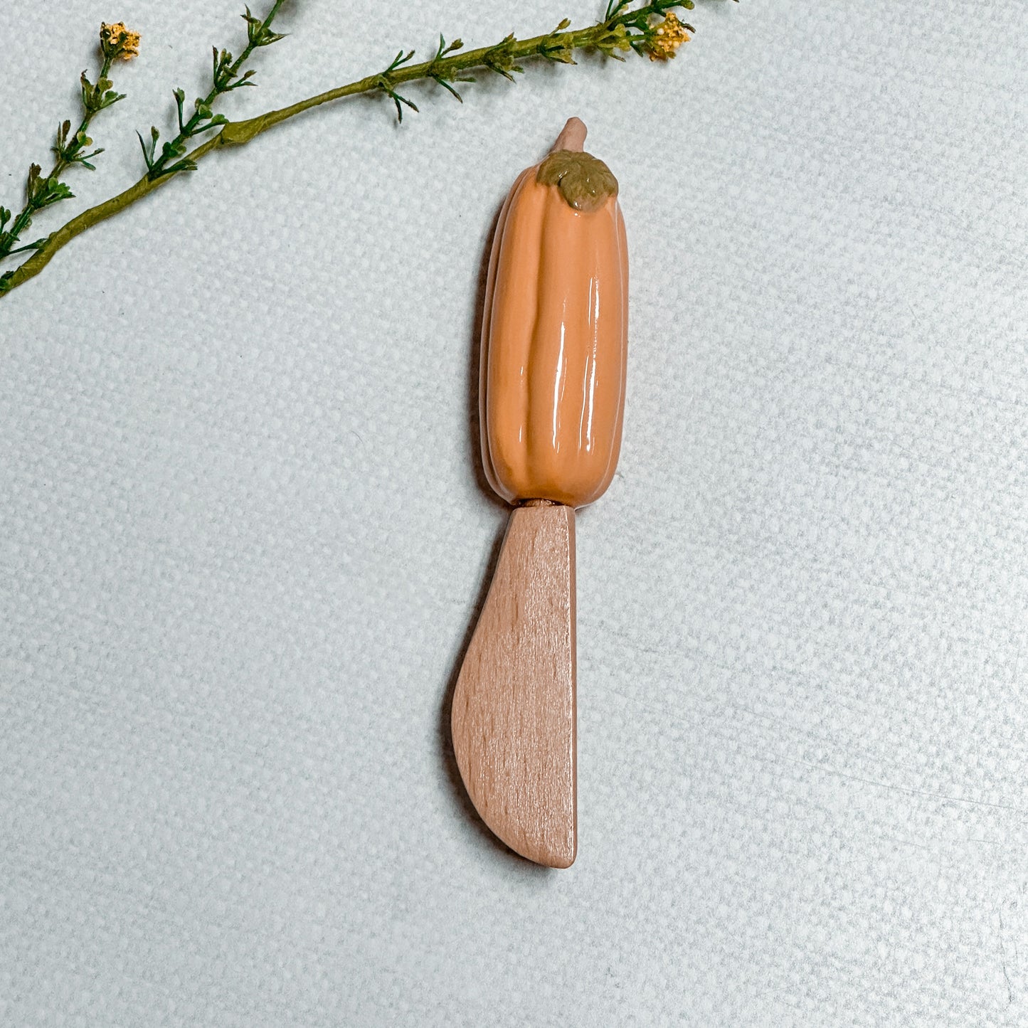 Mud Pie Pumpkin Spreader with orange pumpkin on a linen background.