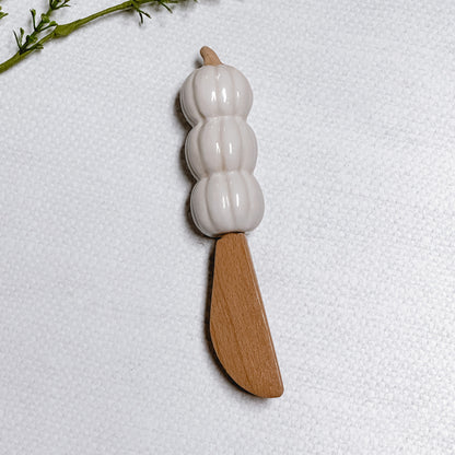 Mud Pie Pumpkin Spreader with three white stacked pumpkins on a linen background.