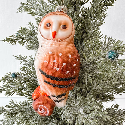 Owl shaped ornament hanging in a tree.