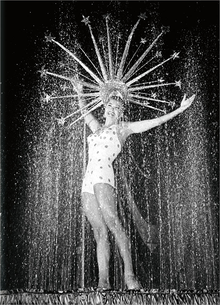 front of card is a woman performer with a sparkly hat and outfit onstage on a black background
