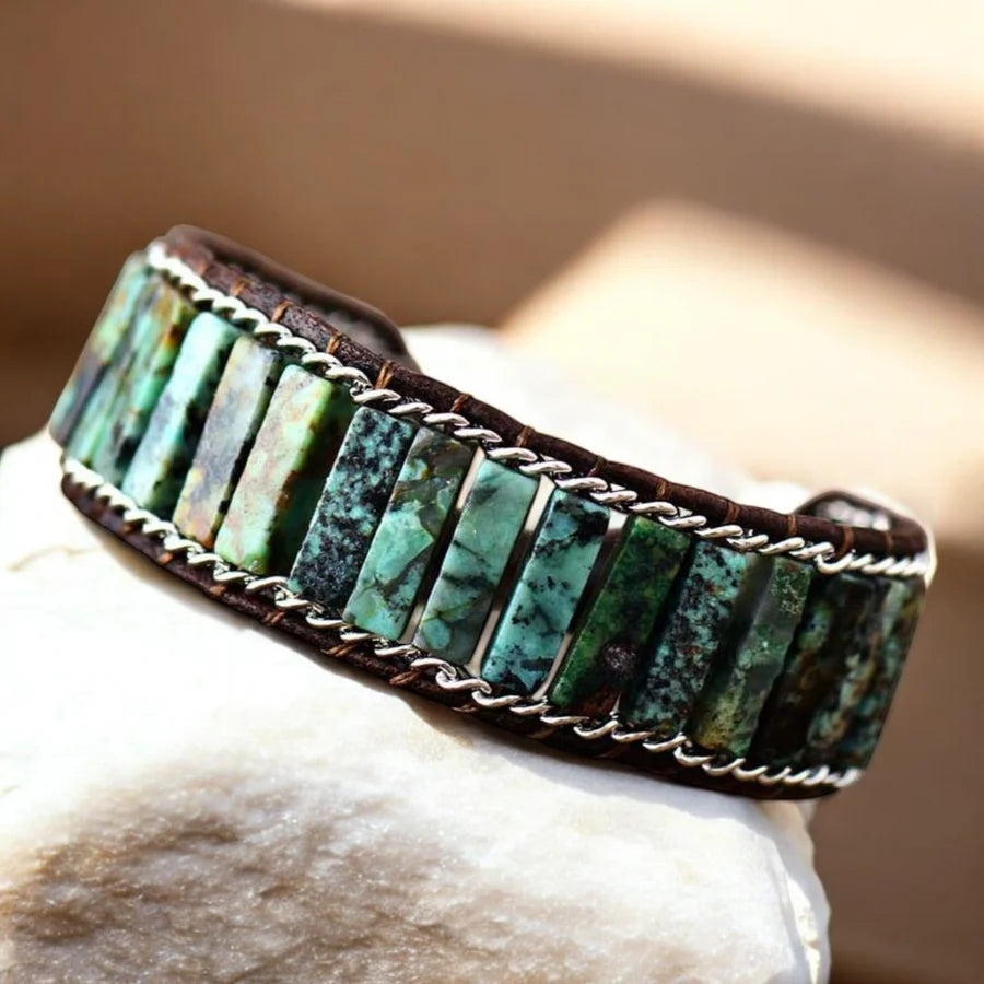 Turquoise stone bracelet with silver accents on a stone surface with a blurred background