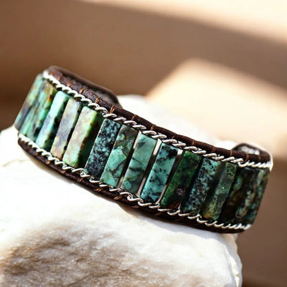 Turquoise stone bracelet with silver accents on a stone surface with a blurred background