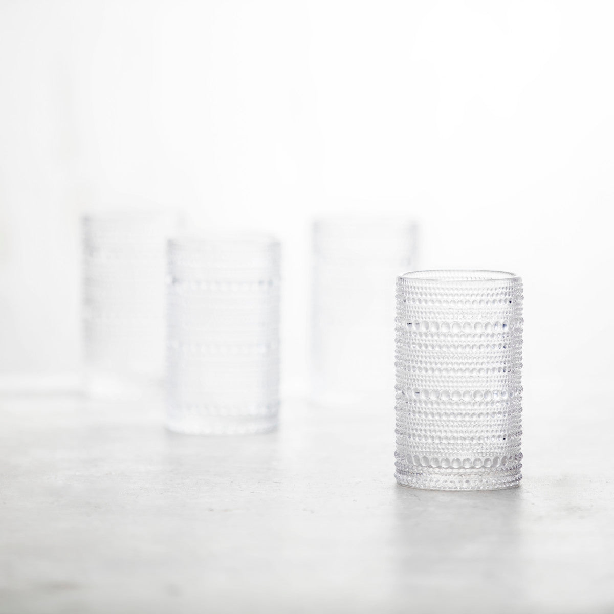 4 clear jupiter iced beverage glasses arranged on a countertop.