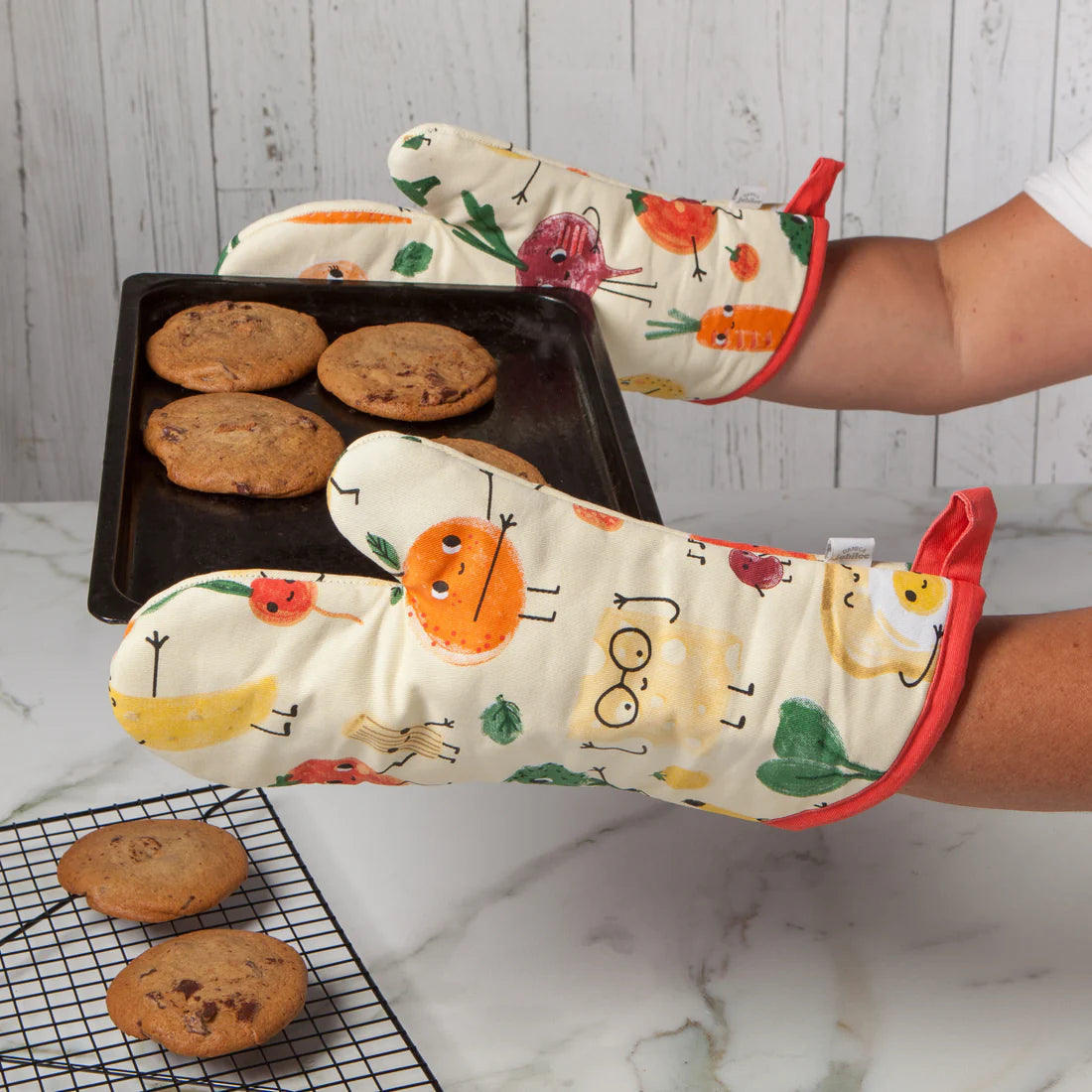 hands wearing funny food mitts and holding a tray of baked cookies