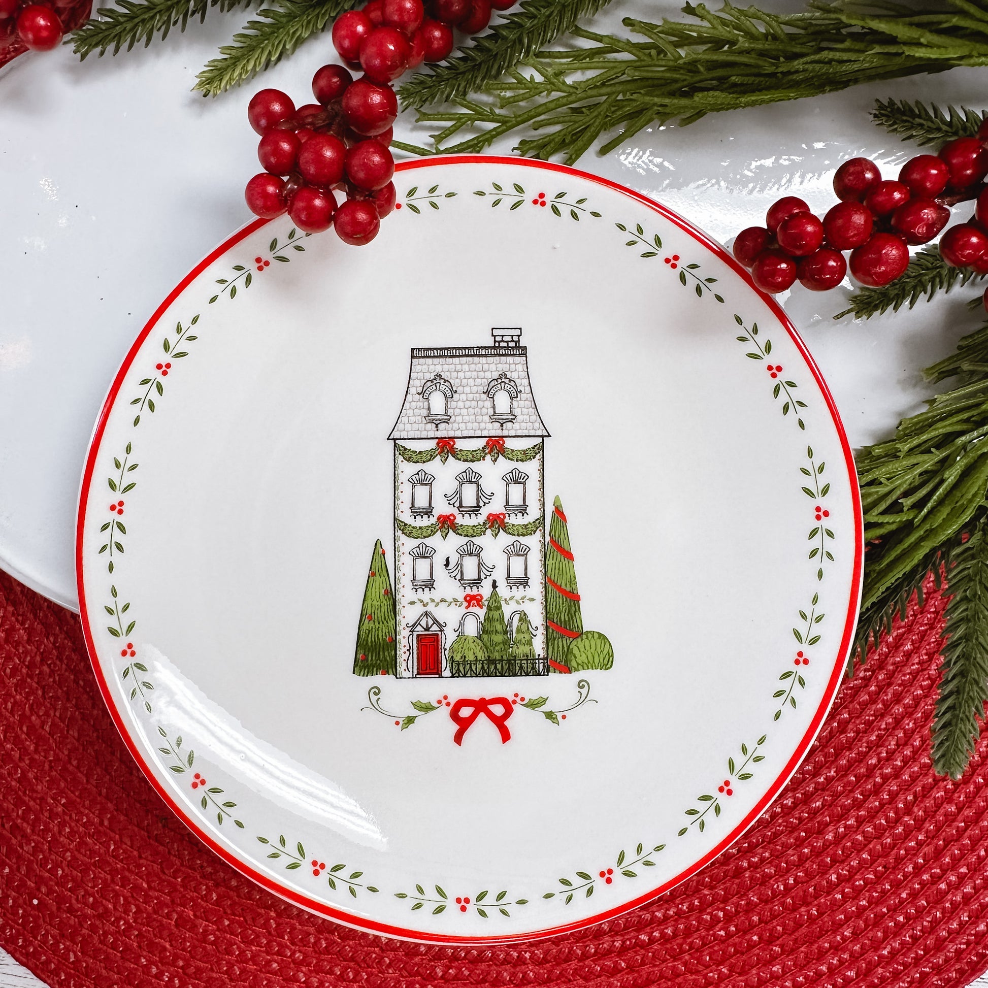 black and white line drawn four story house with green trees, leaf border on white ceramic plate. 