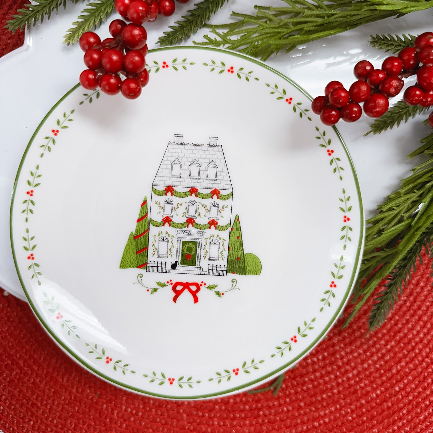 Black and white line drawn three story house with green door, & a leaf border on white ceramic plate.