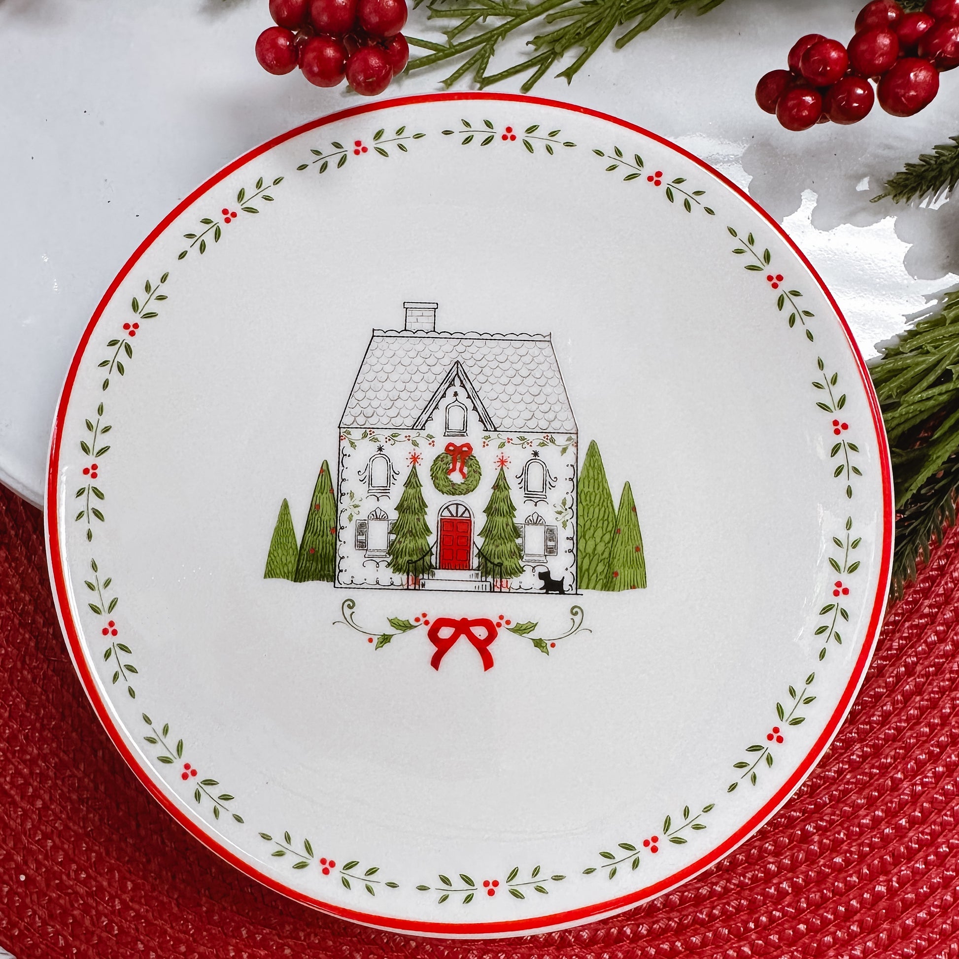 White ceramic plate with leaf border and a black and white line drawn three story house with red door.
