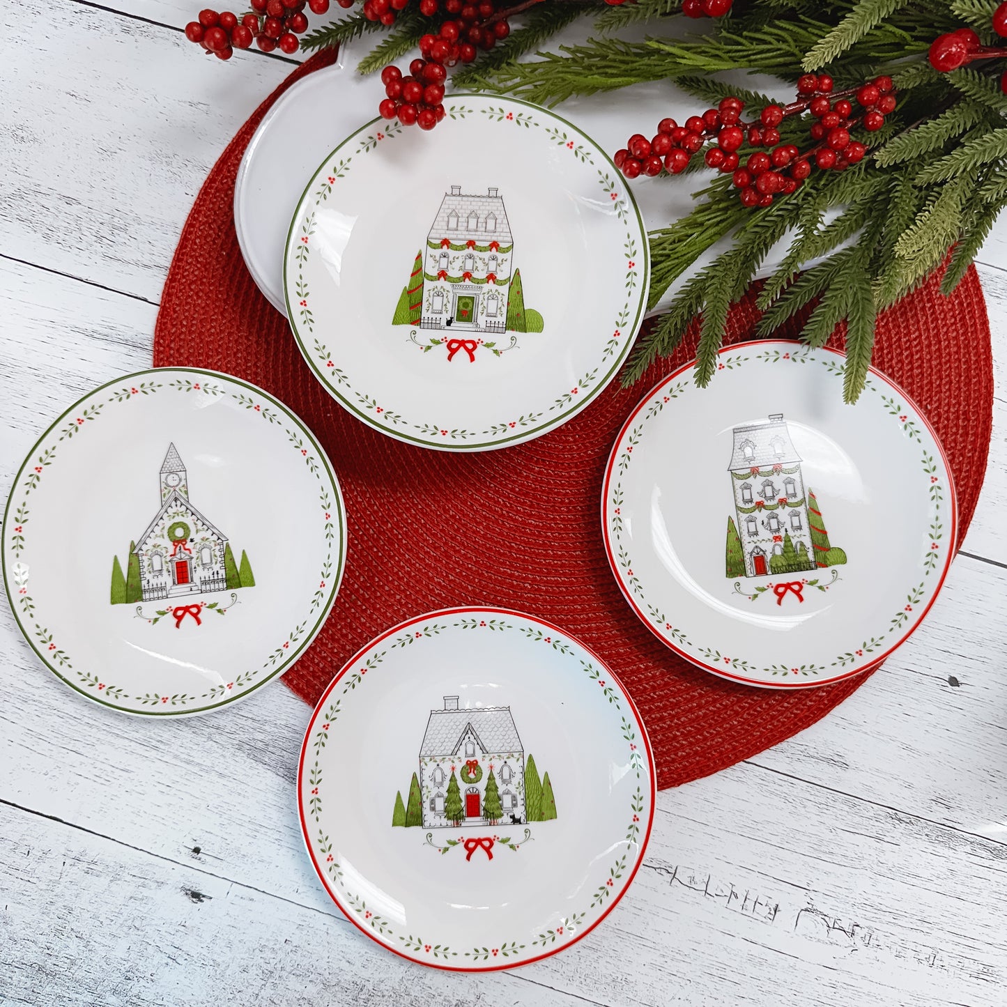 four line drawn red, black, and green ceramic plates on a round red placemat set atop a wooden table.