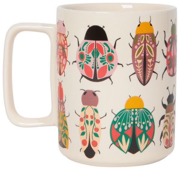 other side of white amulet studio mug is white with scarabs and beetles in hues of pinks and greens