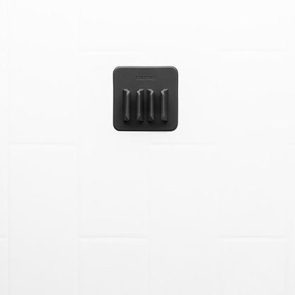 black silicone toothbrush holder on a white tile background.