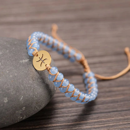 Pisces bracelet draped on a stone on a wooden table.