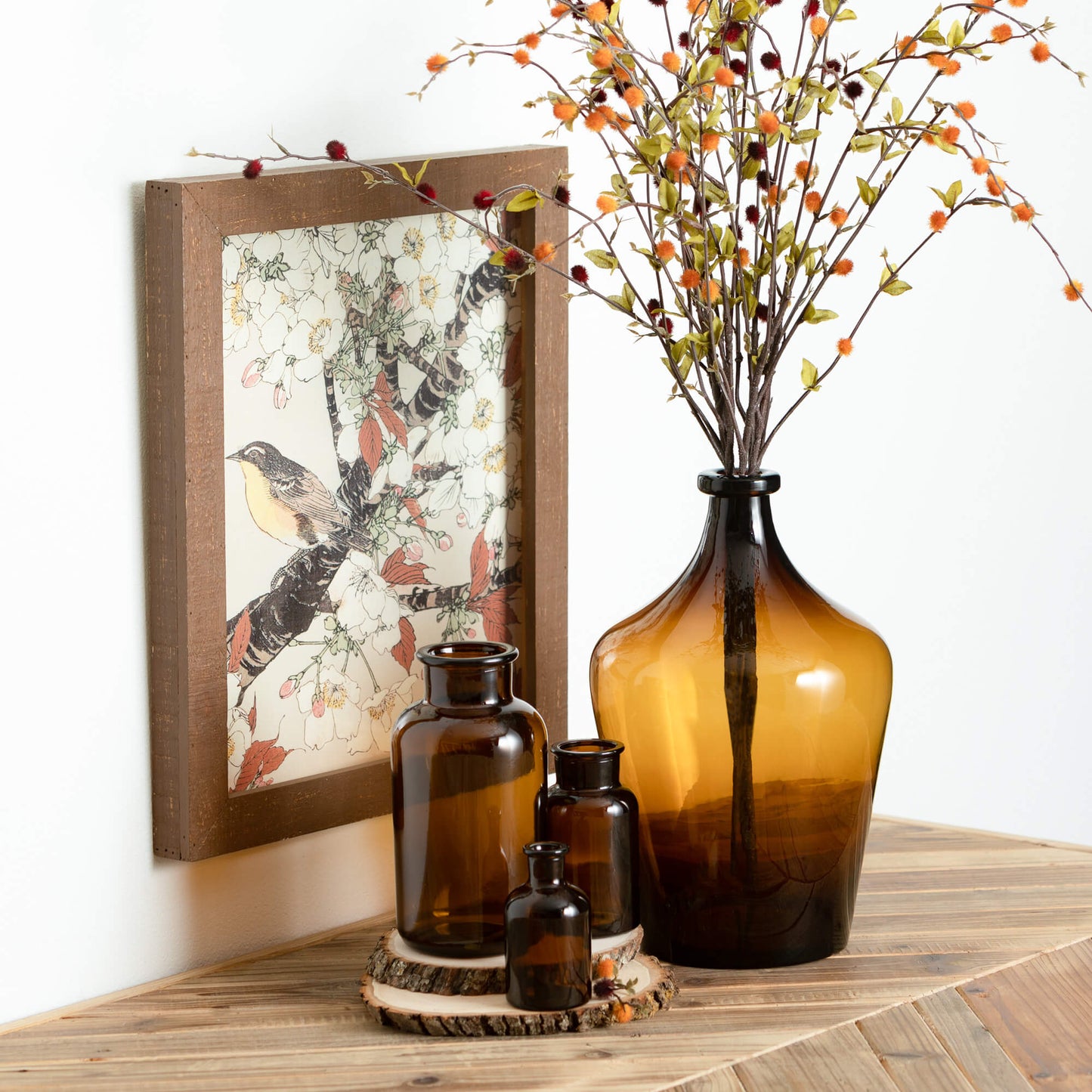 framed bird artwork hanging above a table with amber vases